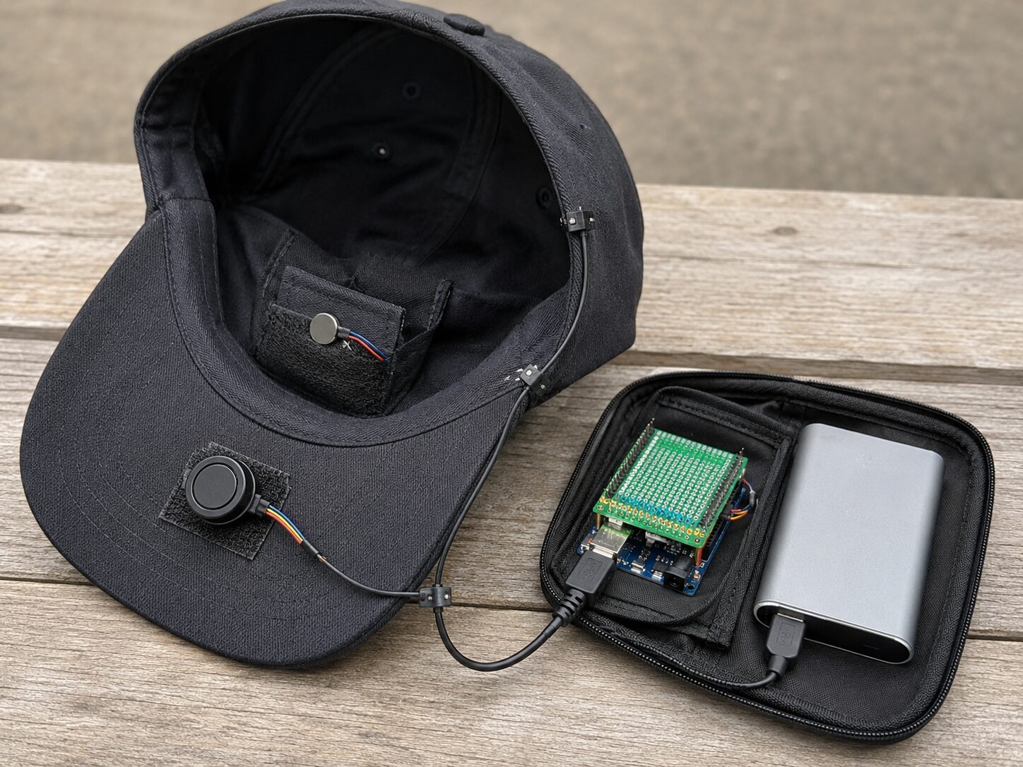 Concept mockup of the open cap showing the vibration motor pocket in the sweatband and a small pouch holding the controller board and power bank.